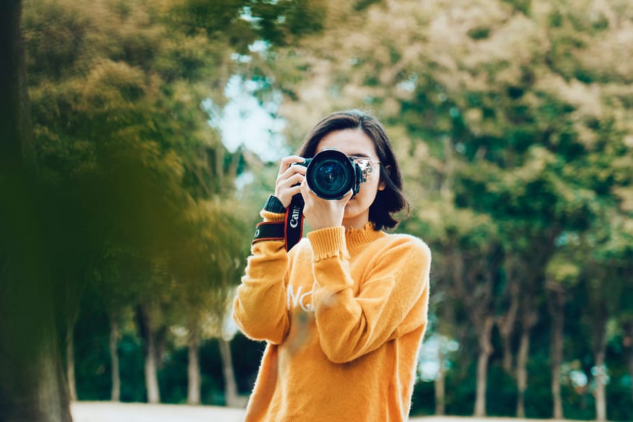 a lady in yellow holding a camera